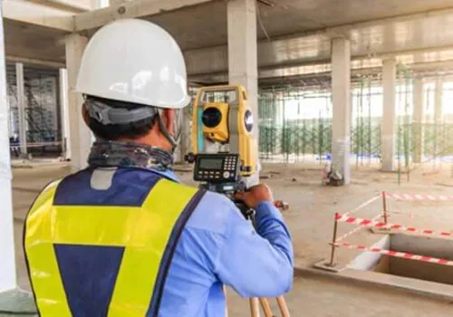 A professional setting up for property surveying for a facility under construction