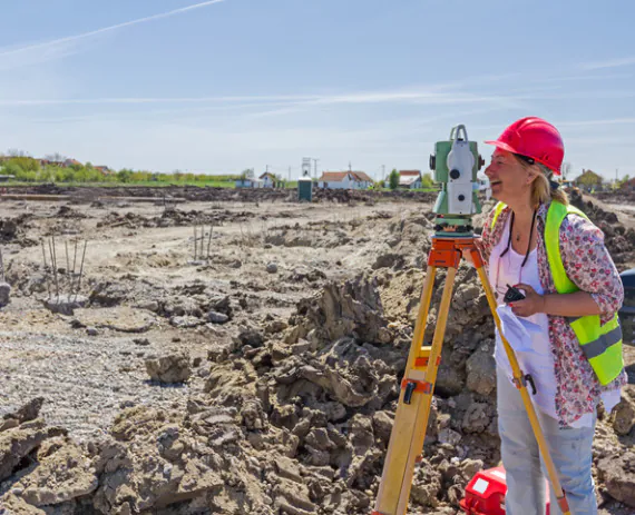 A professional surveyor performing ALTA Surveys in Bettendorf IA on a piece of land getting ready for construction