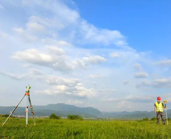 A professional surveyor on a piece of land conducting Solar Farm Surveys in Peoria IL