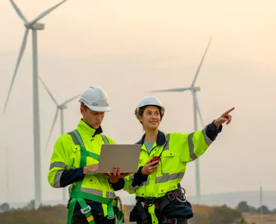 Two engineers from Austin Engineering stand on a wind far and perform Drone Surveys by the Quad Cities